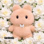 Plush pendant with 'Gardenia' name tag among white gardenia flowers